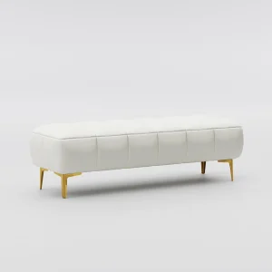 White tufted bench with gold legs on a plush carpet, placed near a large window with horizontal blinds and white slippers in front.