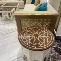 A refined lounge vignette blending geometric artistry, plush seating, and layered marble textures. Round wooden side table with star inlay, cream tufted sofa with teal cushions, marble flooring