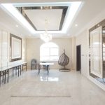 High ceilings and mirrored accents elevate this luminous lounge into a statement of modern elegance. Spacious modern room with marble flooring, chandelier, arched window, vertical wall panels, and glass-topped tables in a luxurious interior.