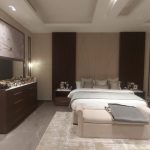 Layered textures and soft lighting create a bedroom that’s both elegant and deeply personal. Luxurious bedroom with large bed, cushioned bench, vertical wood paneling, dark dresser, floral wall panels, and tiled flooring in a neutral-toned interior.