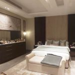 Layered textures and warm neutrals create a serene, luxurious bedroom with personalized charm. Modern bedroom with white and beige bedding, dark paneled accent wall, upholstered bench, and dresser with decorative items in a neutral-toned interior.