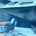 “Navy wave wall + pink gloss desk = closing deals in actual art.” A futuristic executive office featuring a dramatic undulating wall clad in vertical glossy navy-blue slats that create a flowing wave effect. A sleek angular desk in glossy pink-and-black lacquer sits in the foreground with a blue leather office chair, set on high-gloss white marble flooring under a sculptural ceiling with geometric light fixtures.