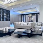 Neutral tones and clean lines define this elegant living space, where form meets function in every detail. Modern living room with grey sofa, black coffee tables, built-in shelving, and black-framed glass doors in a minimalist neutral-toned interior.