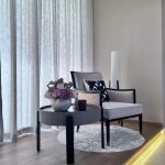 A serene reading corner with floral accents and ambient lighting brings warmth to this minimalist space Minimalist reading nook with a white armchair, round side table, floral arrangement, and warm LED floor lighting in a softly lit modern interior.