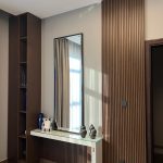Clean lines and layered textures bring warmth and sophistication to this modern accent wall setup. Interior with vertical wood slat wall, white console table, mirror, shelving unit, and decorative accents.