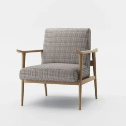 Mid-century modern armchair with checkered brown and beige upholstery, angled wooden legs, and natural wood armrests, placed on a patterned rug over hardwood flooring.