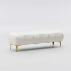 White tufted bench with gold legs on a plush carpet, placed near a large window with horizontal blinds and white slippers in front.